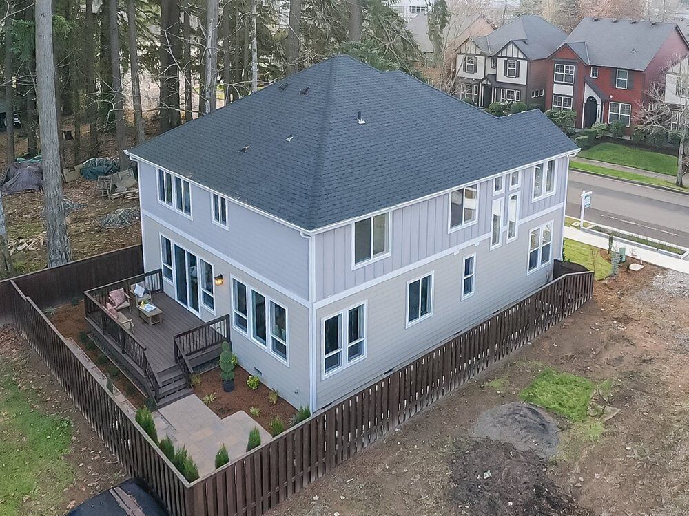 Drone photo of the back and side angle of a two story house showing the back and side yard view.