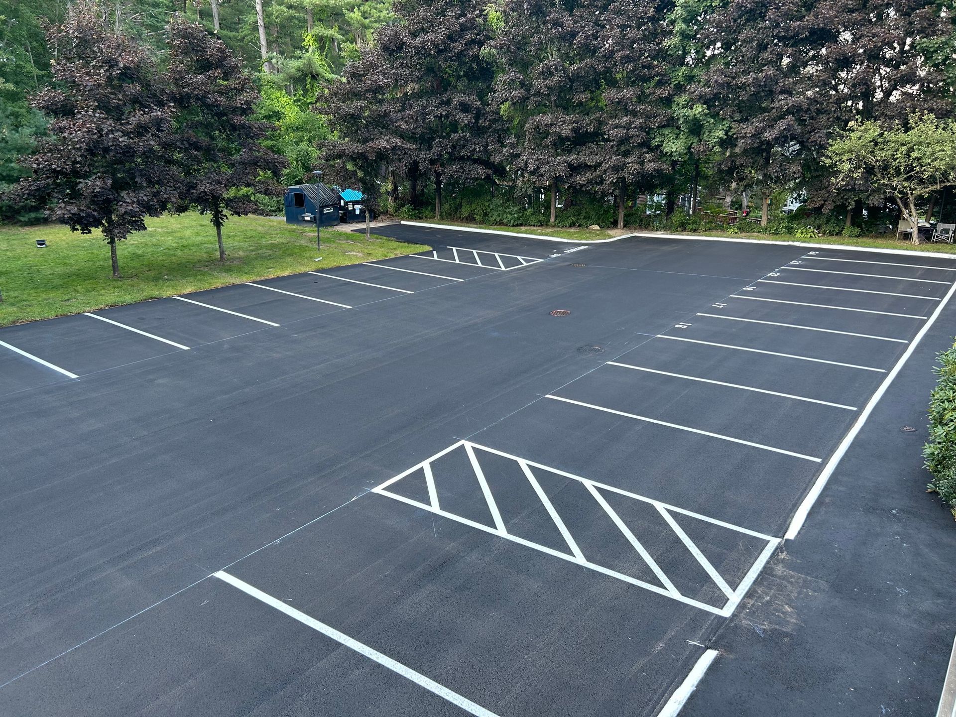 Newly paved asphalt parking lot with white painted parking space lines.