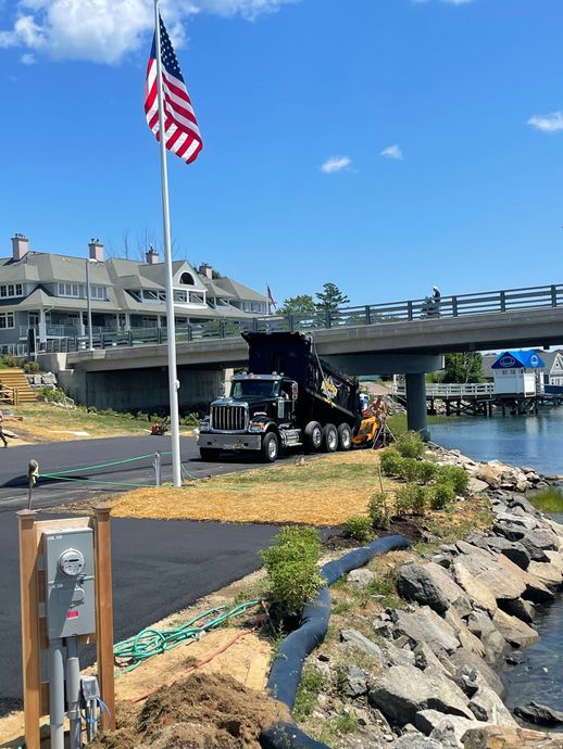 Black dump truck unloading material on Bailey Island by Asphalt Experts