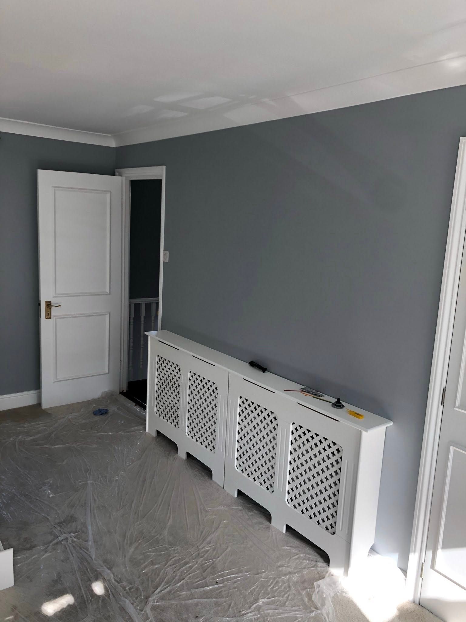 Empty room with grey walls, white trim, and a white radiator cover.