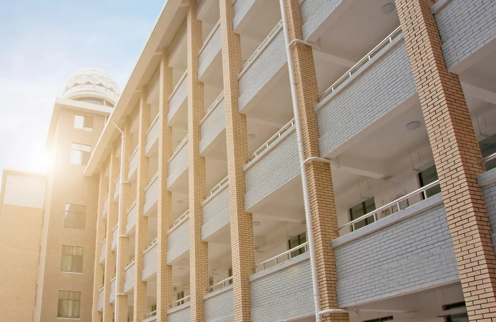 The sun is shining through the windows of a large brick building.