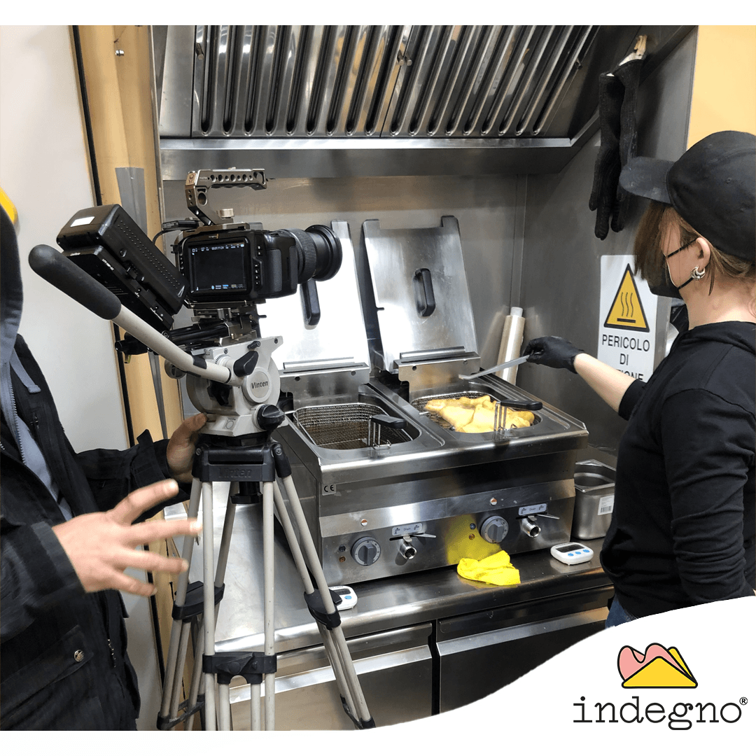 Una telecamera su un treppiede riprende una persona che indossa un'uniforme e una mascherina nere