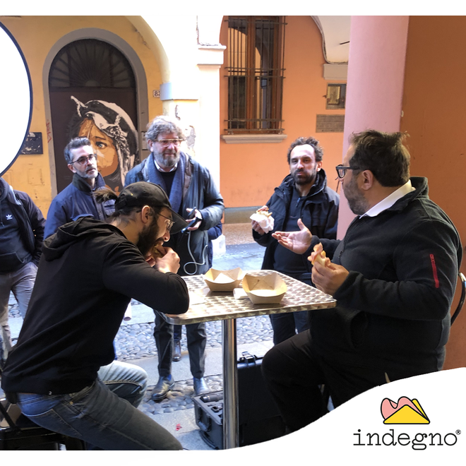 Un gruppo di persone sedute attorno a un tavolino all'aperto, sotto un arco di pietra