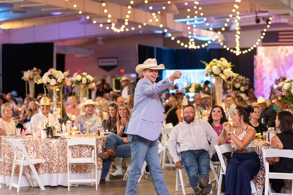 a man in a cowboy hat is smiling in front of a crowd at an event