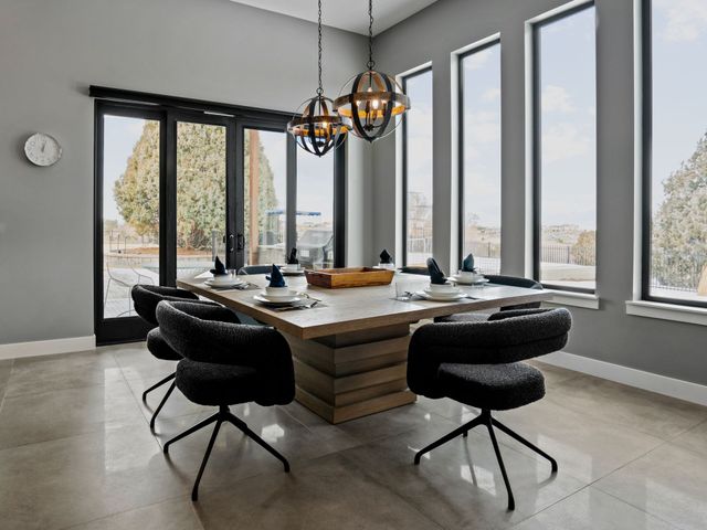 A dining room with a table and chairs and a lot of windows.