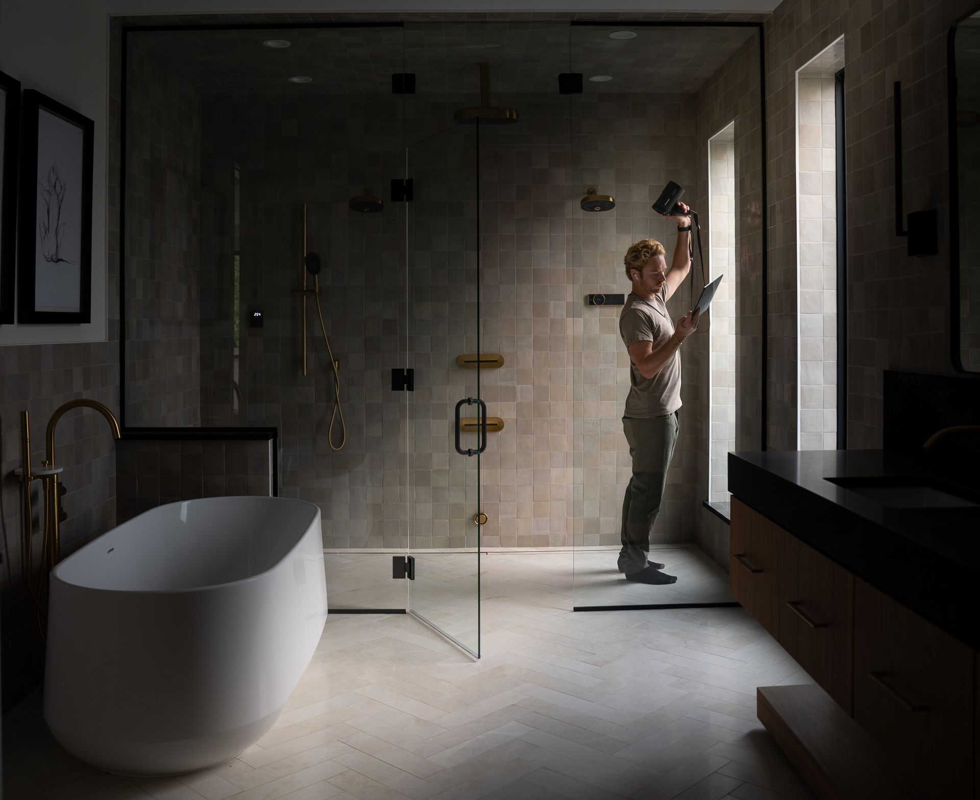 A man is blow checking the lights in a bathroom next to a bathtub.