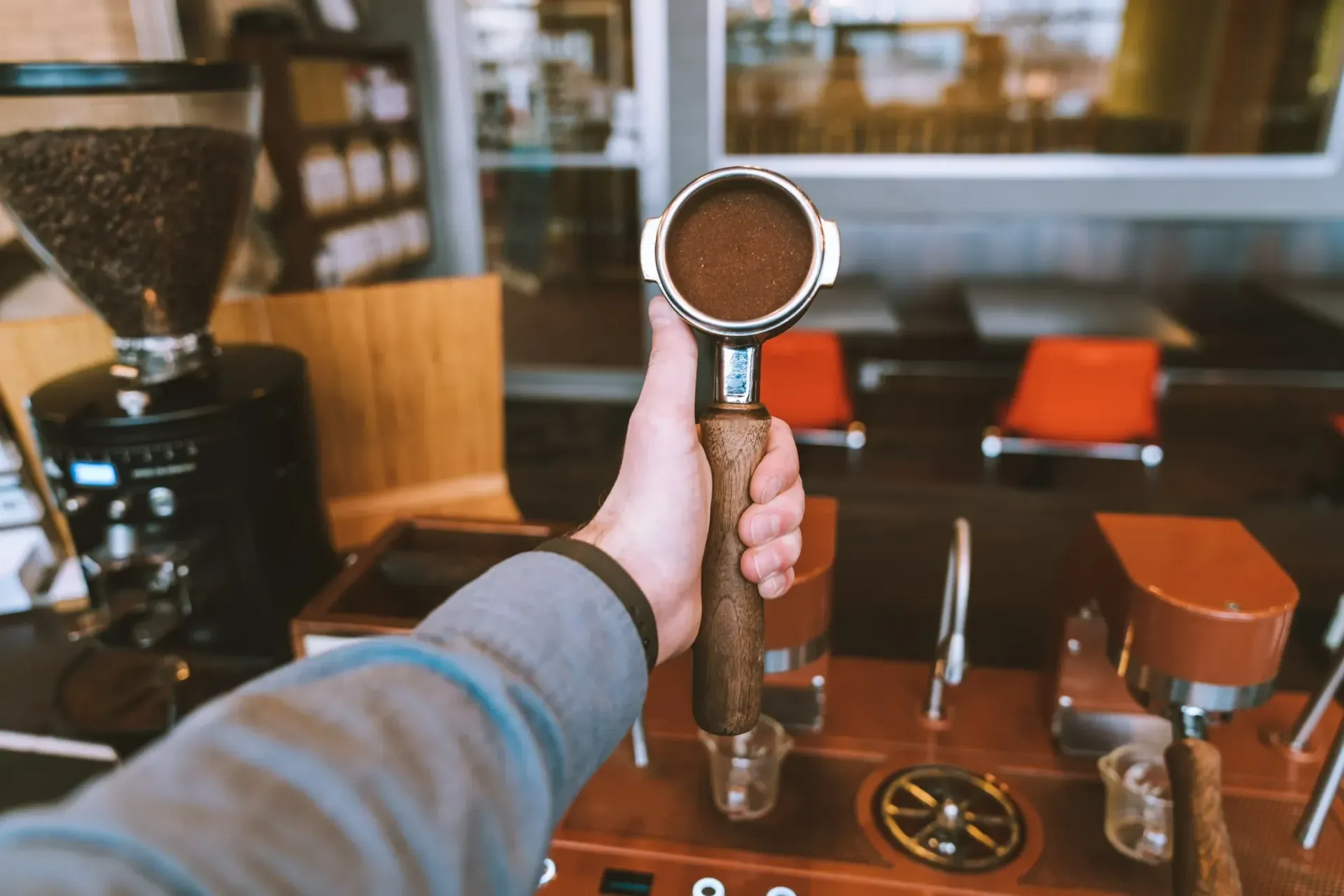 A person is holding a coffee filter in their hand in a coffee shop.