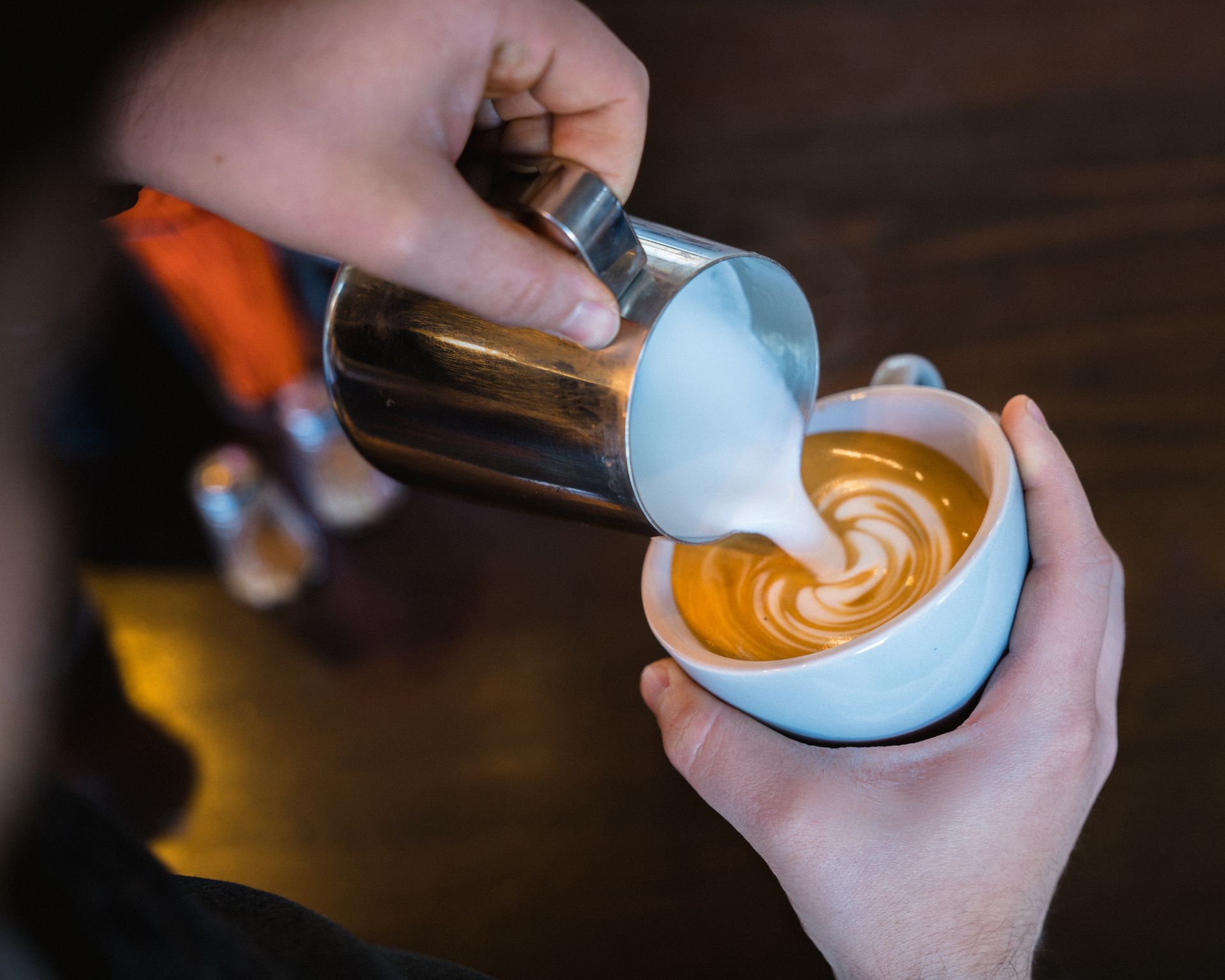 A person is pouring milk into a cup of coffee