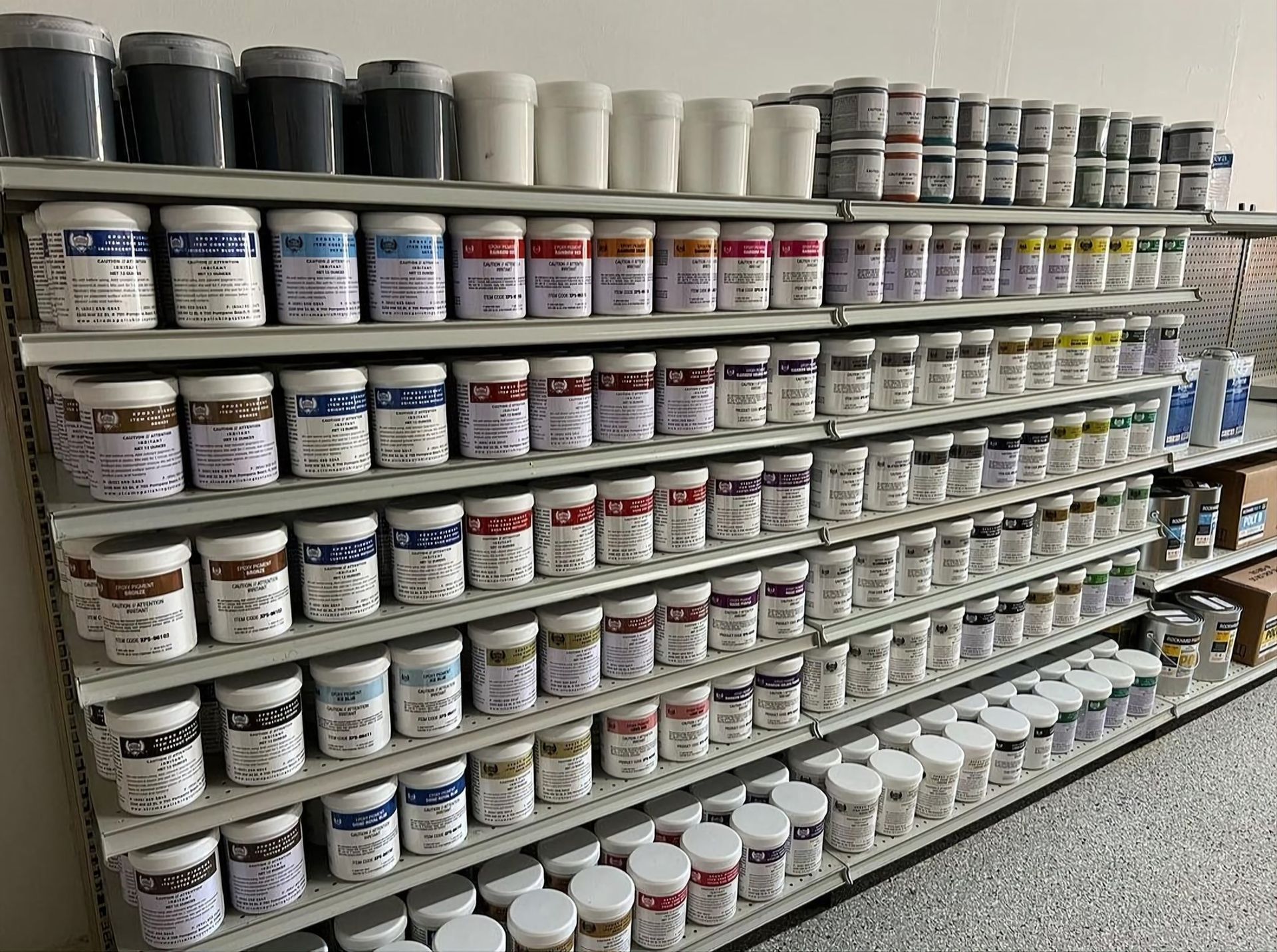 Shelves stocked with rows of paint cans and jars in a store aisle