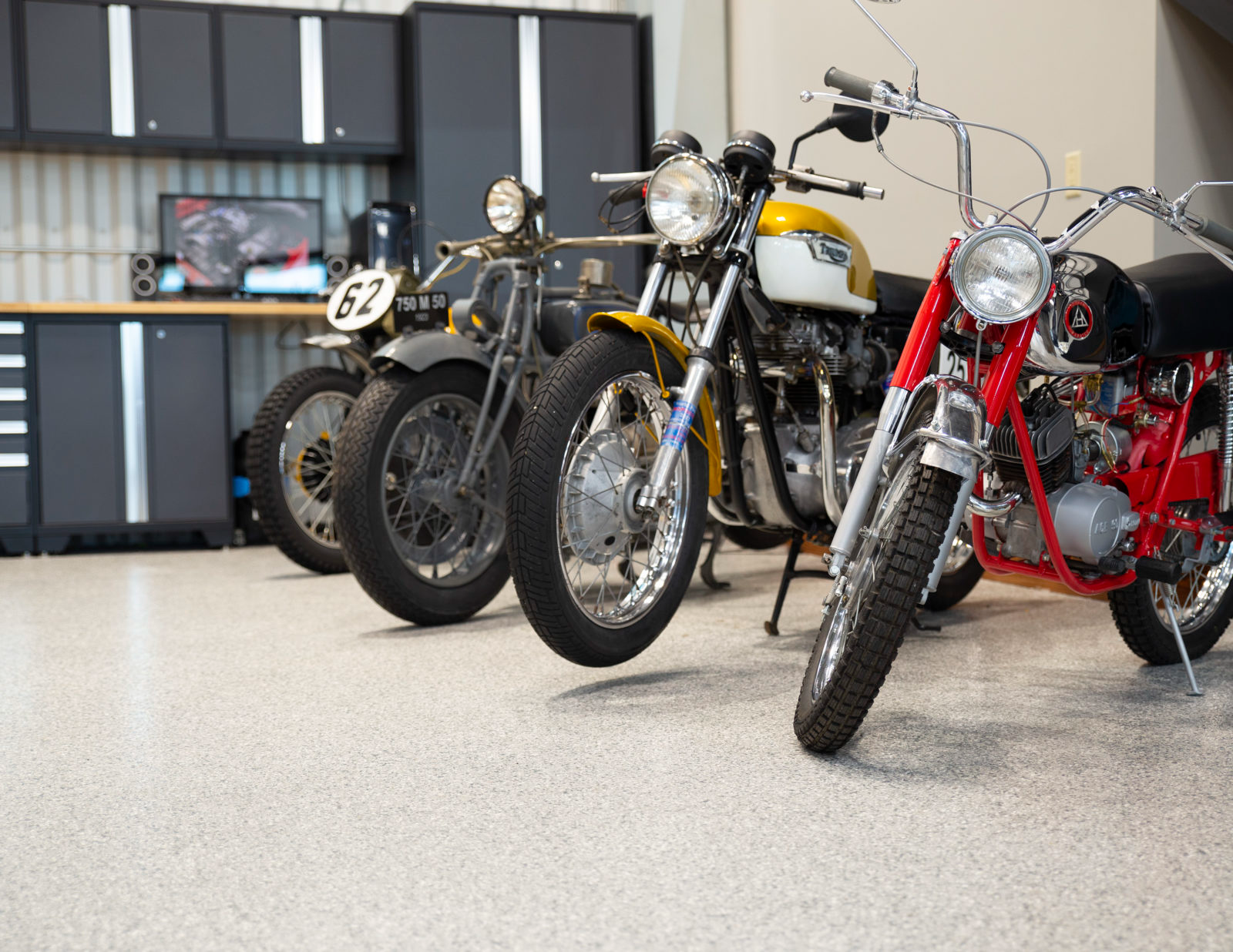 Row of custom motorcycles parked in a showroom, including black, yellow, and red bikes