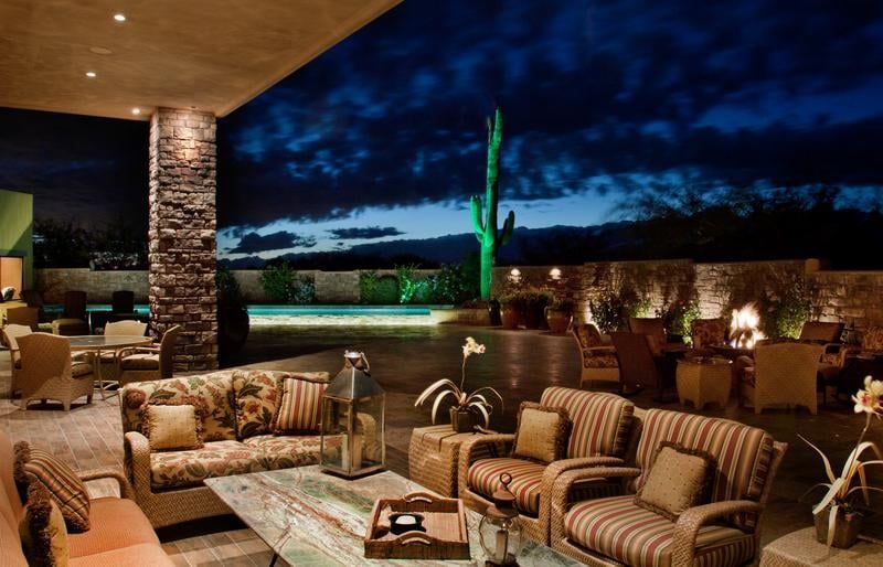 Outdoor lounge area at dusk with sofas, pool, and desert landscape.