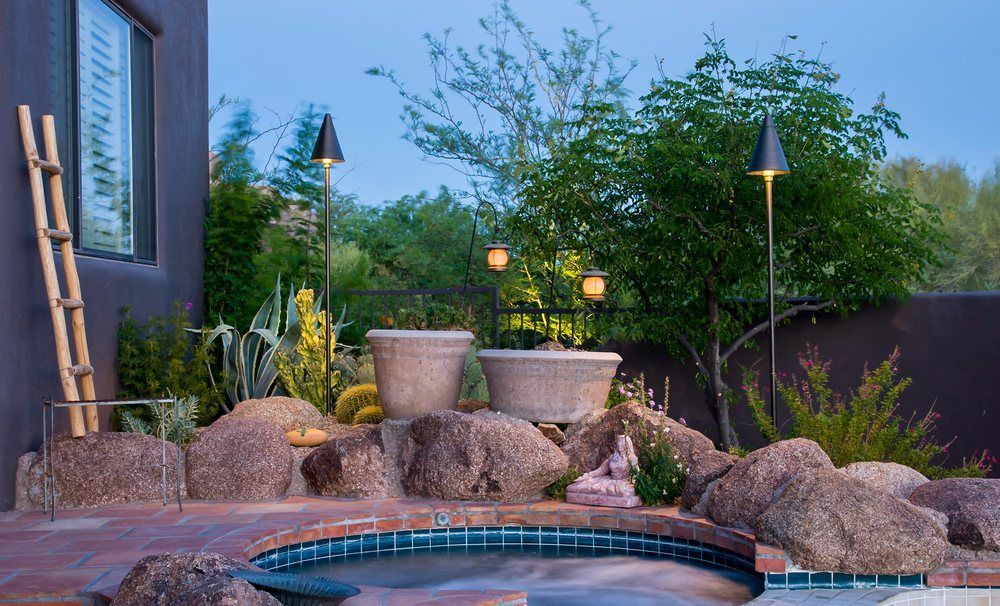 Backyard landscaping with a small pool, rock formations, and ambient lighting.