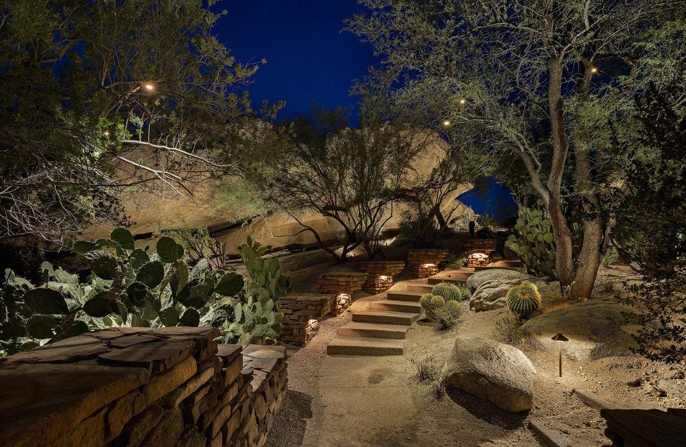 Nighttime landscape with stone stairs, desert plants, and soft lighting.