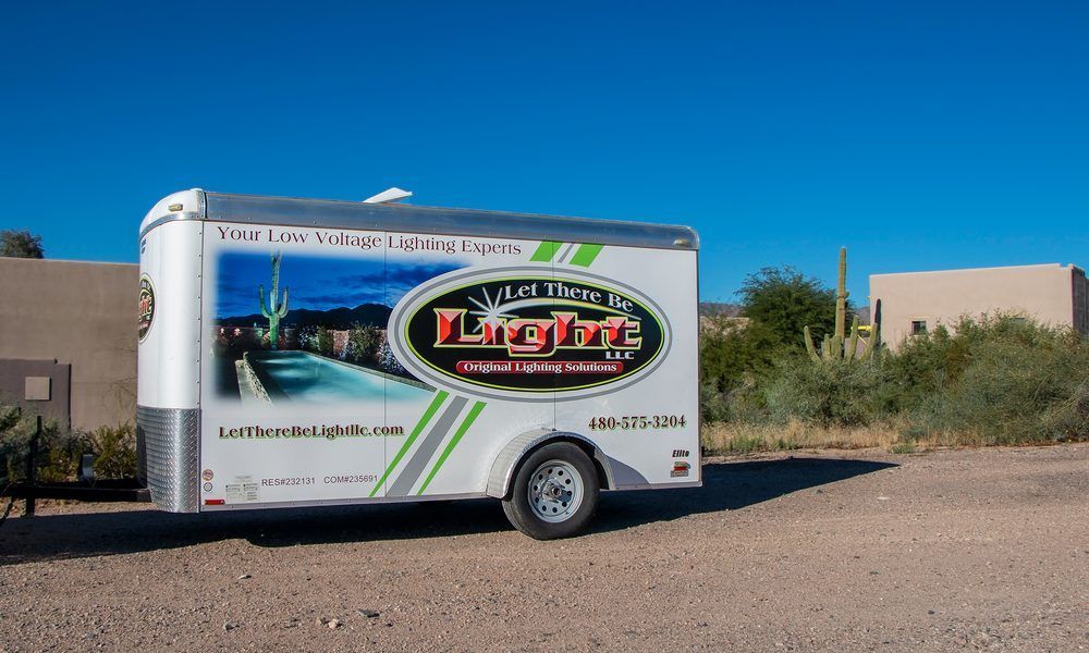 White trailer with company logo, parked outdoors on a sunny day.