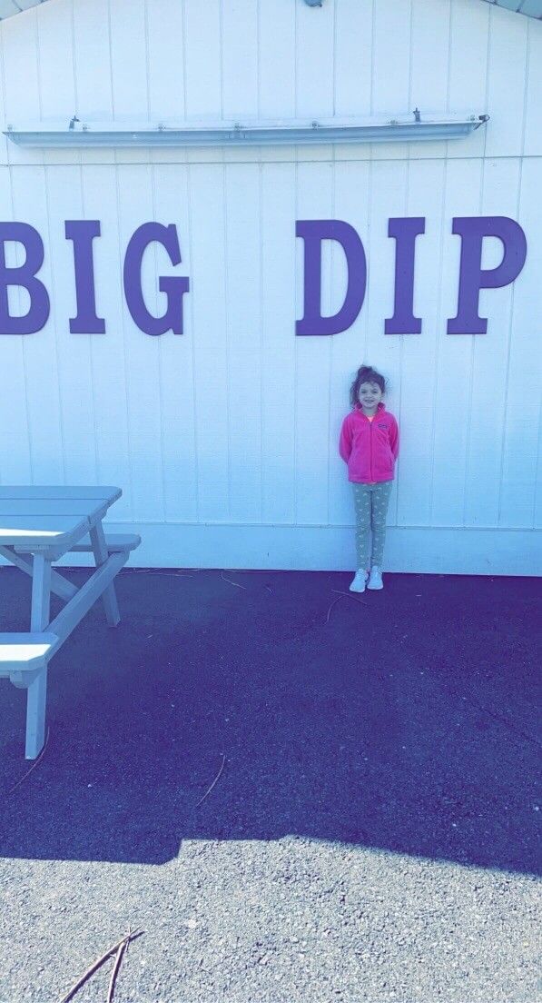 A little girl is standing in front of a big dip sign.