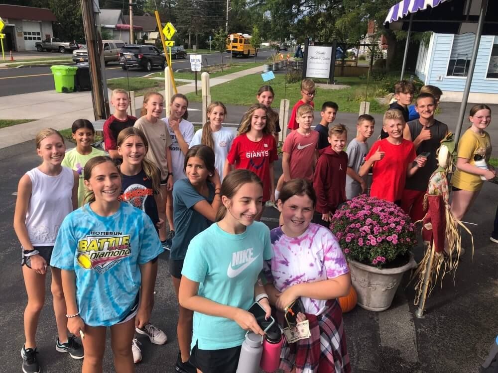 A group of young people are posing for a picture in a parking lot.