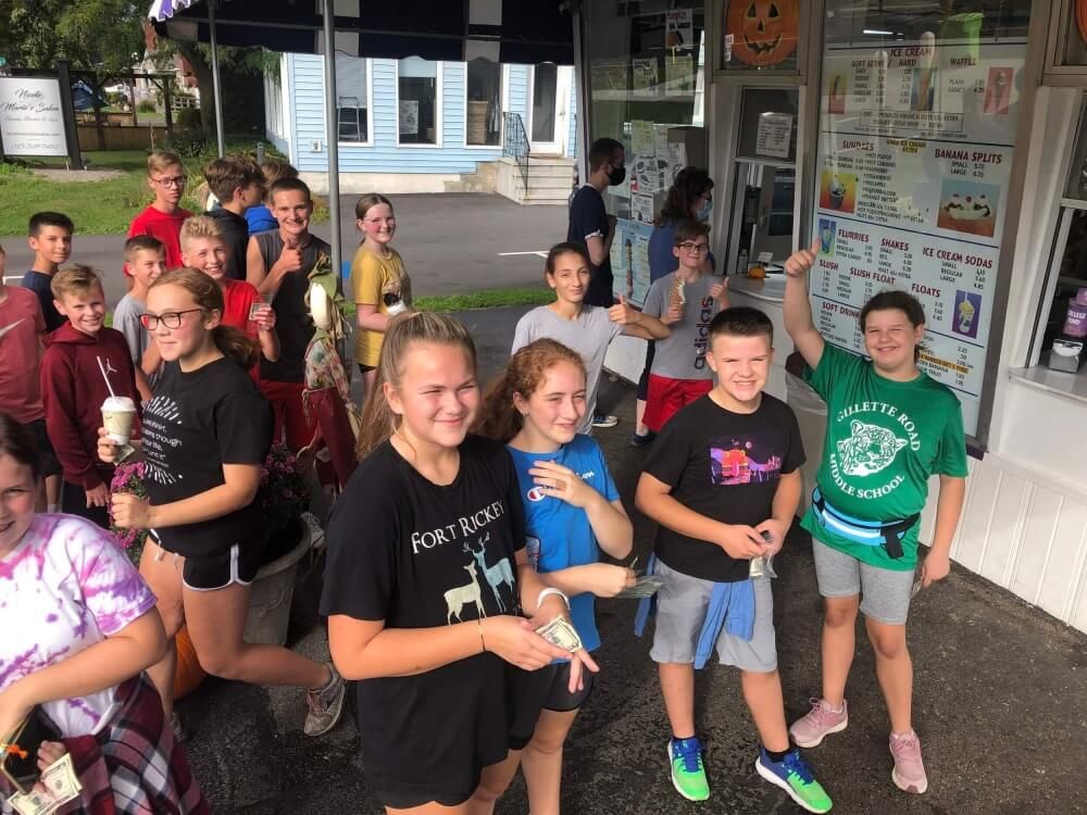 A group of young people are standing in front of an ice cream truck.