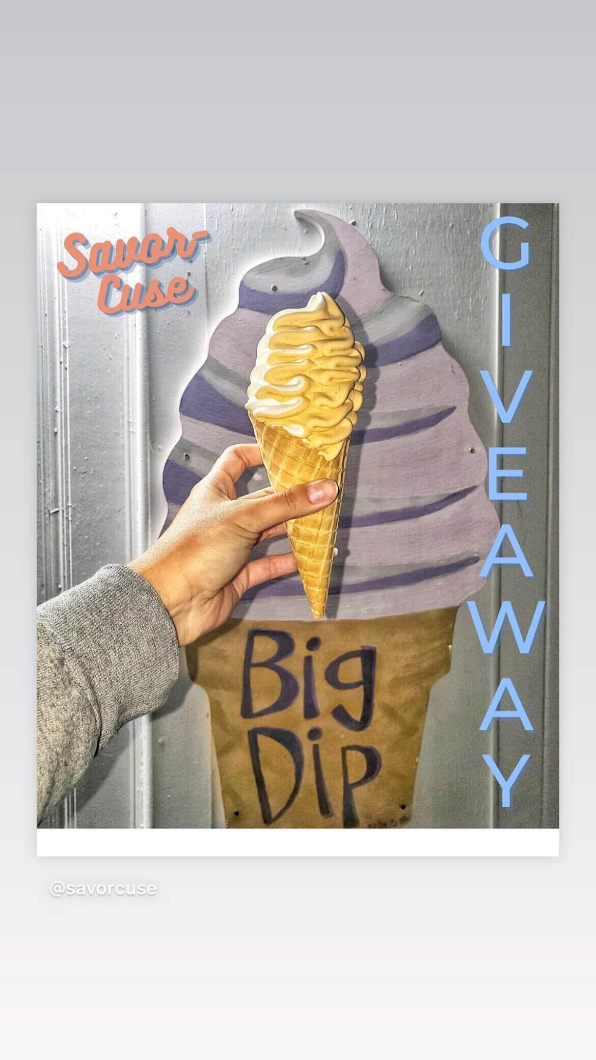 A person is holding an ice cream cone in front of a sign that says big dip.