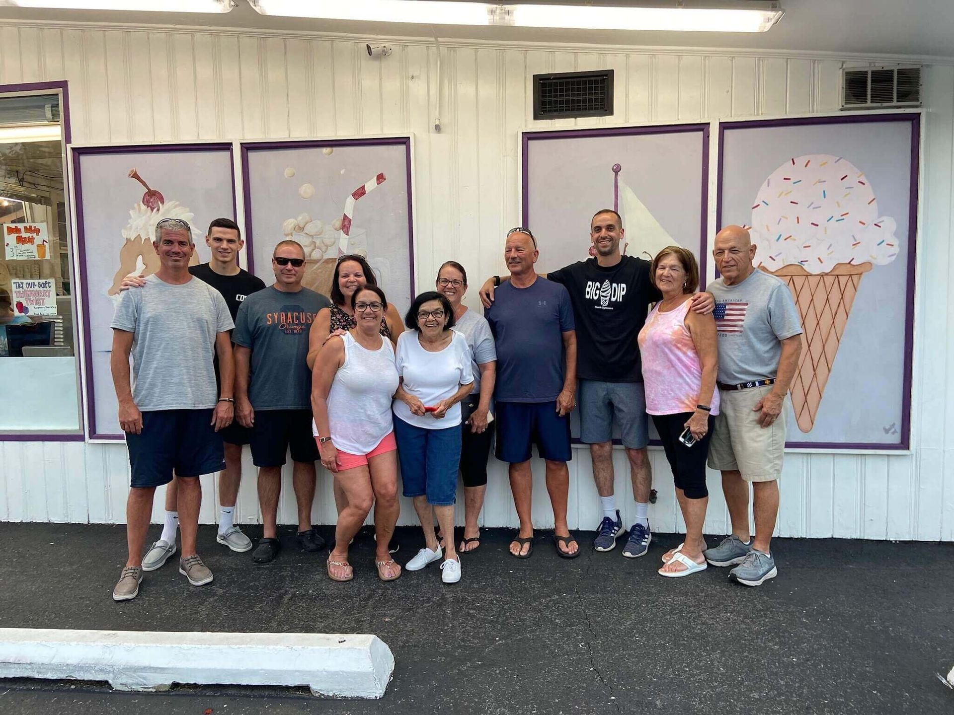 A group of people are posing for a picture in front of an ice cream shop.
