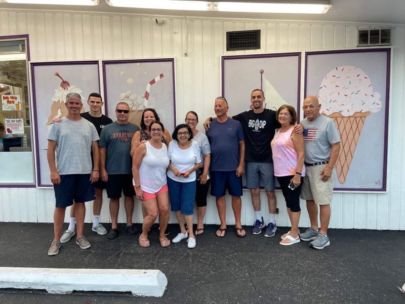 A group of people are posing for a picture in front of an ice cream shop.