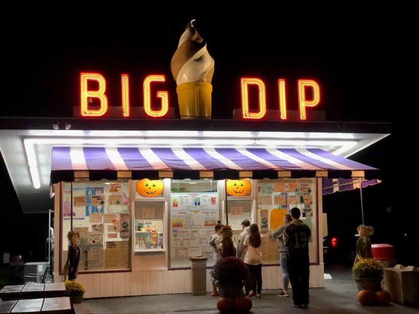 A group of people standing outside of a big dip ice cream shop