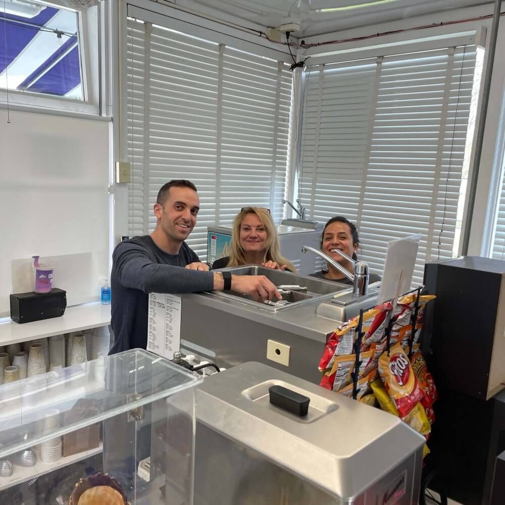 A man and two women are sitting at a counter in a kitchen.