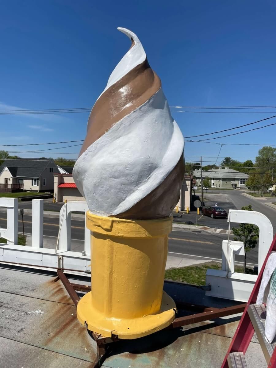 A large ice cream cone is sitting on top of a roof