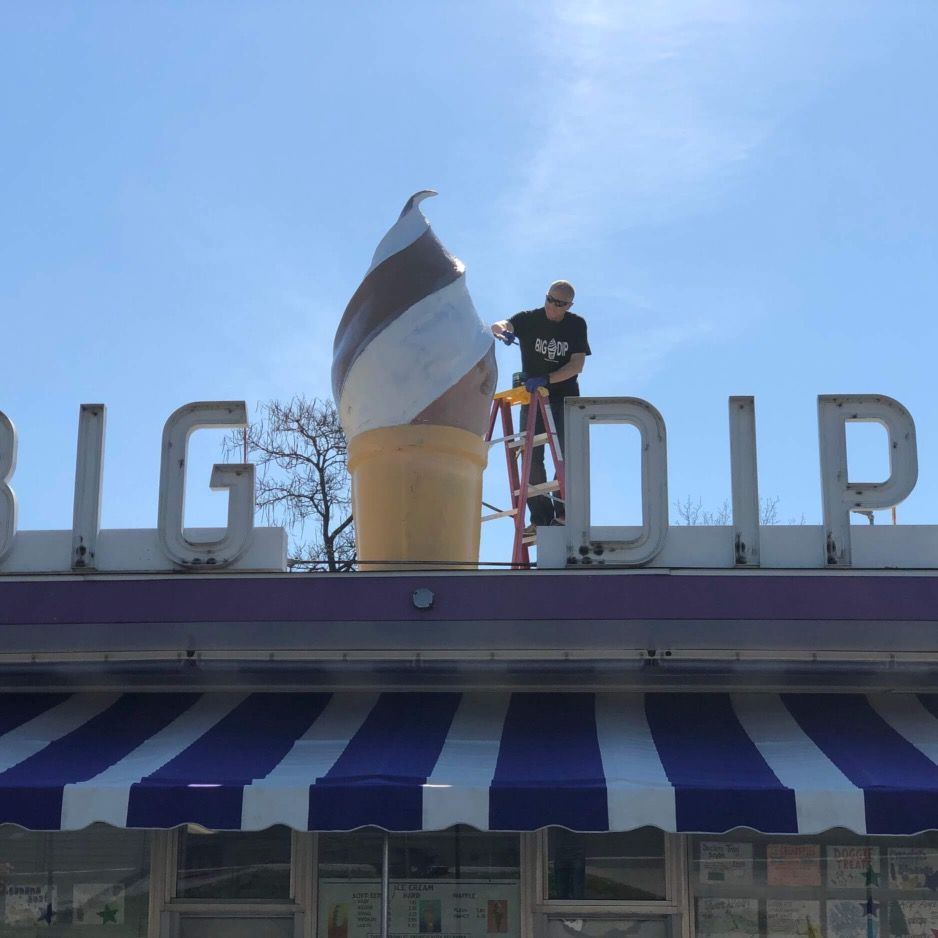A man stands on a ladder above the big dip sign