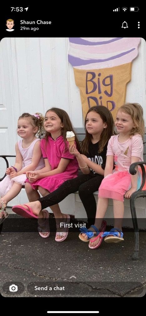 A group of young girls are sitting on a bench eating ice cream.