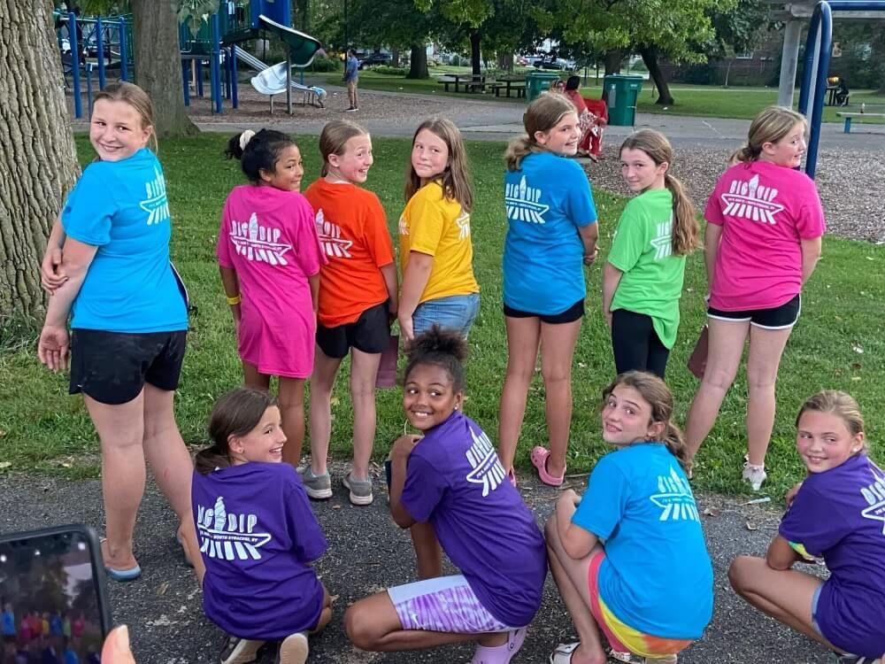 A group of young girls are posing for a picture in a park.