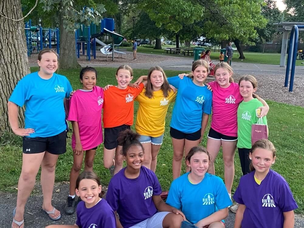 A group of young girls are posing for a picture in front of a playground.