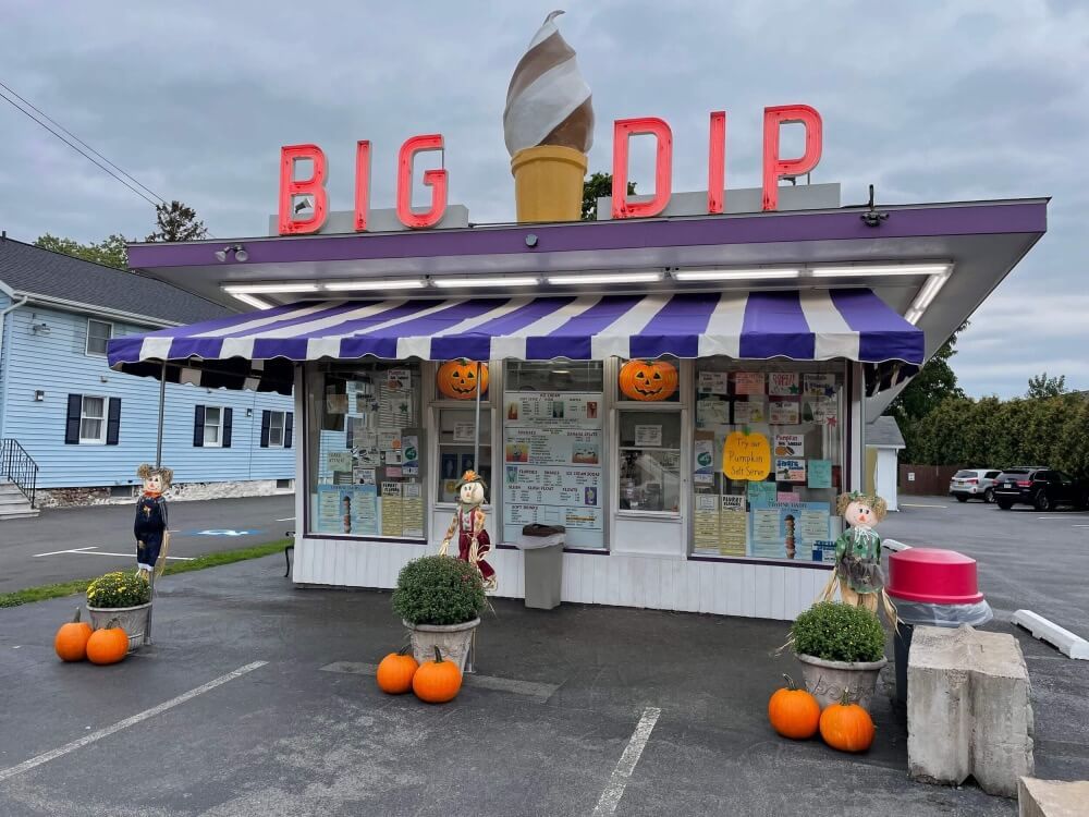A big dip ice cream shop with pumpkins in front of it