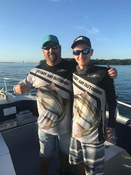 Two men are standing next to each other on a boat in the water.