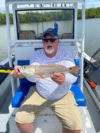 A man is sitting on a boat holding a fish.