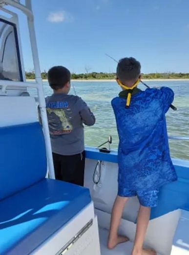 Two boys on a boat one of whom is wearing a shirt that says jaws