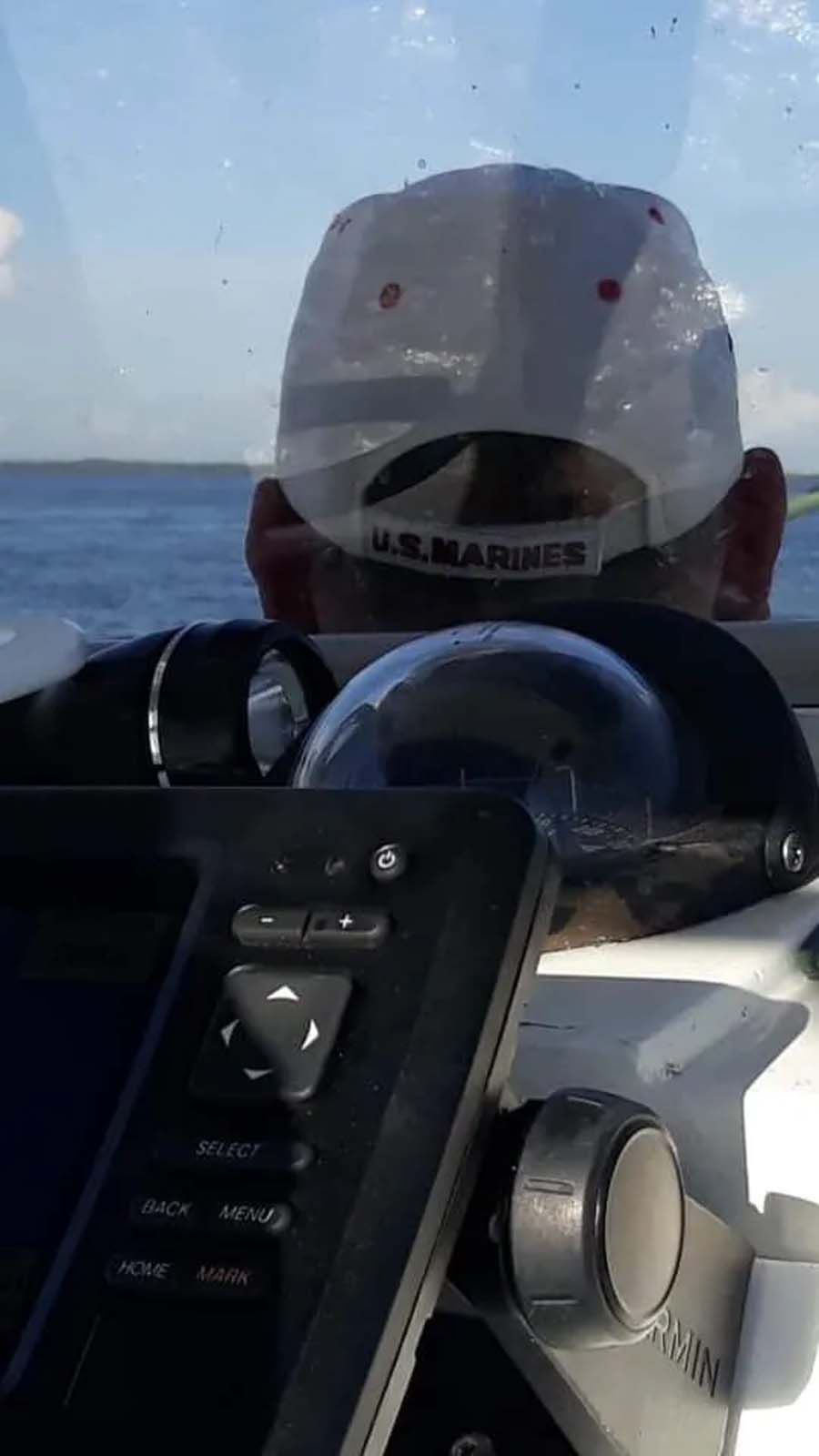 A man wearing a white hat is sitting on a boat looking out the window.