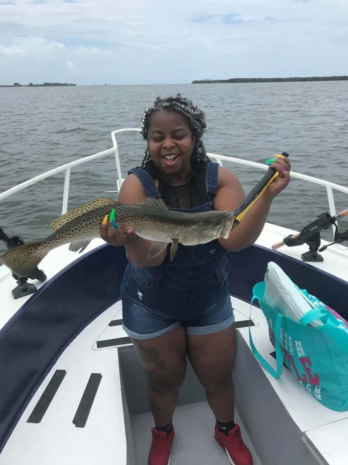 A woman is sitting on a boat holding a fish.