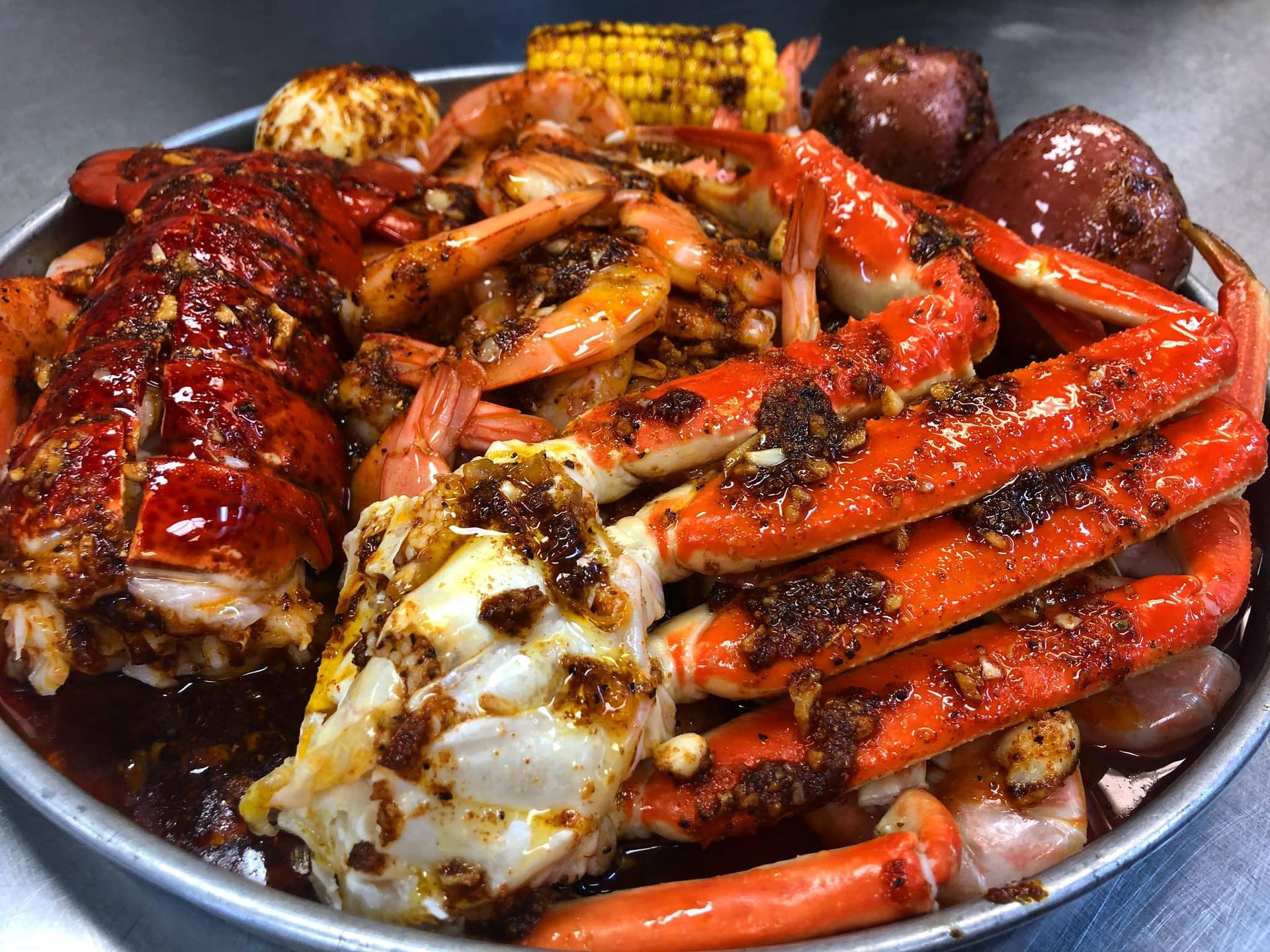 Tasty Crab House's Lets Shake It combo. A pan of Cajun flavor snow crab legs, shrimp with no head, lobster tail, potato, eggs