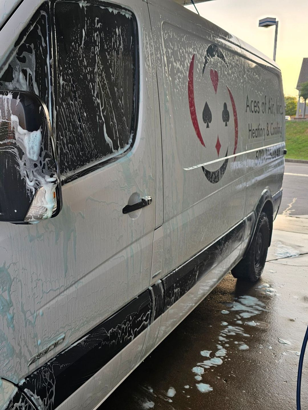 A white van with aces and spades on the side is being washed