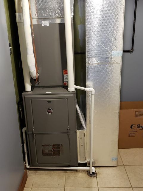 A furnace is sitting in a room next to a door.