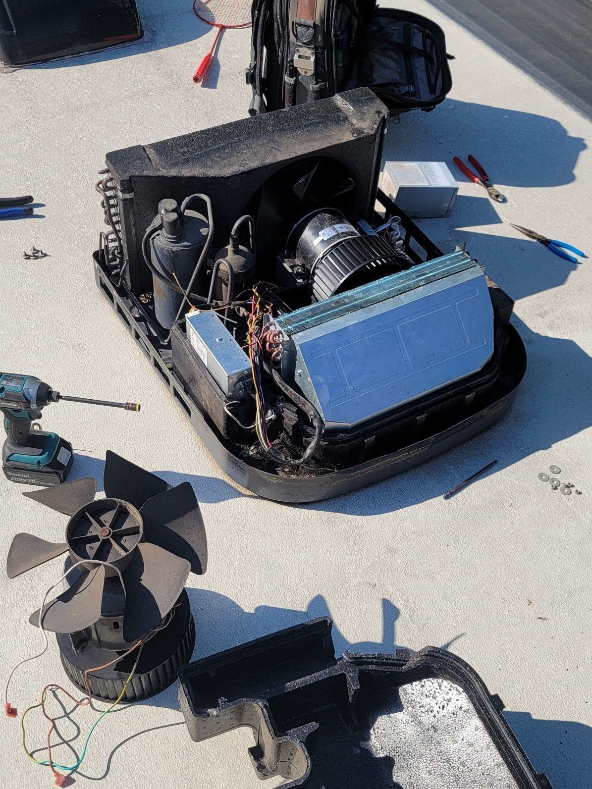 A broken air conditioner is sitting on top of a concrete surface.