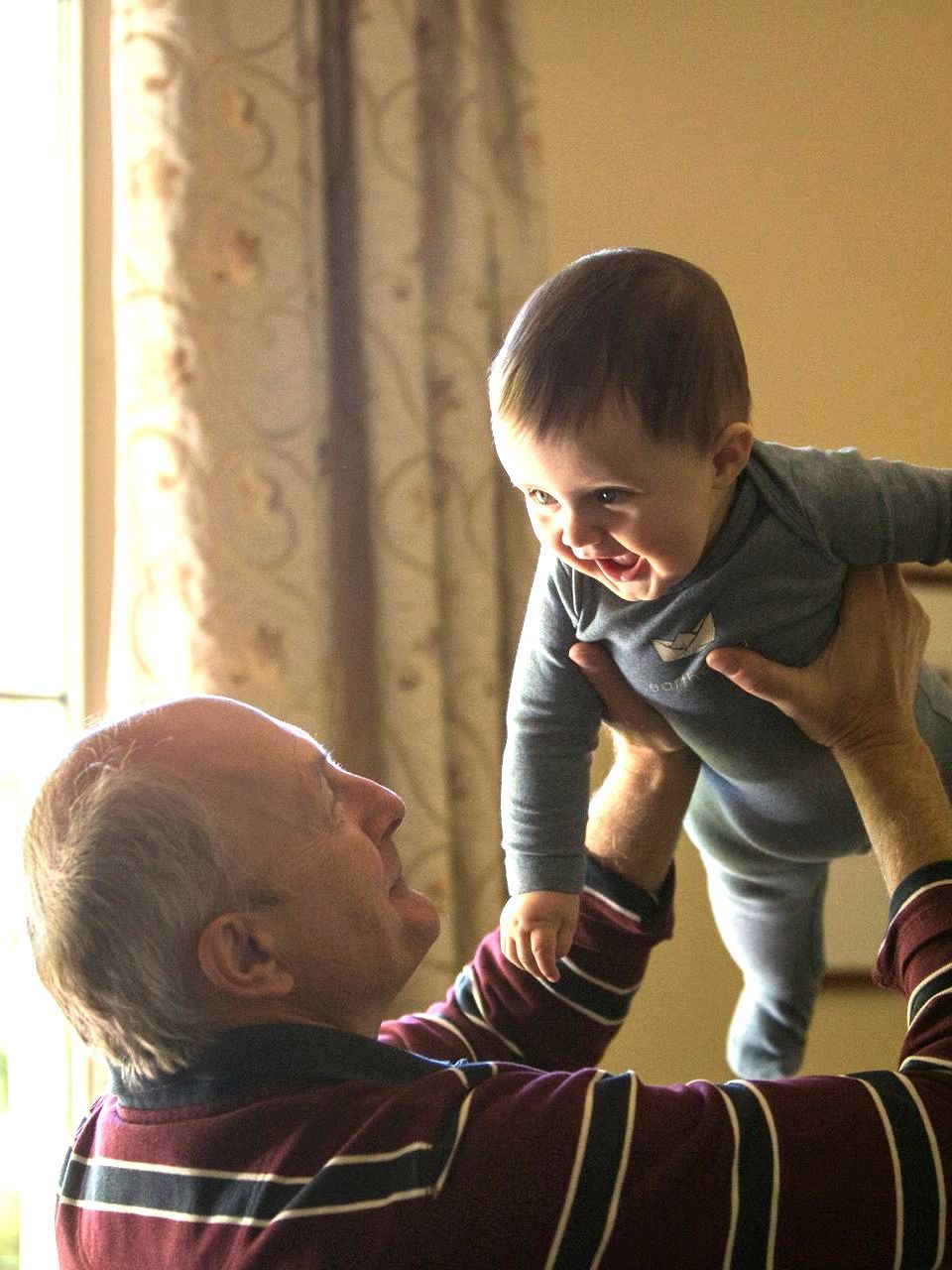 A man is holding a baby up in the air.