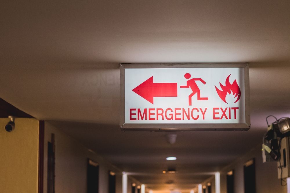 An Emergency Exit Sign Is Hanging from The Ceiling of A Hallway — Imsprint in East Maitland, NSW