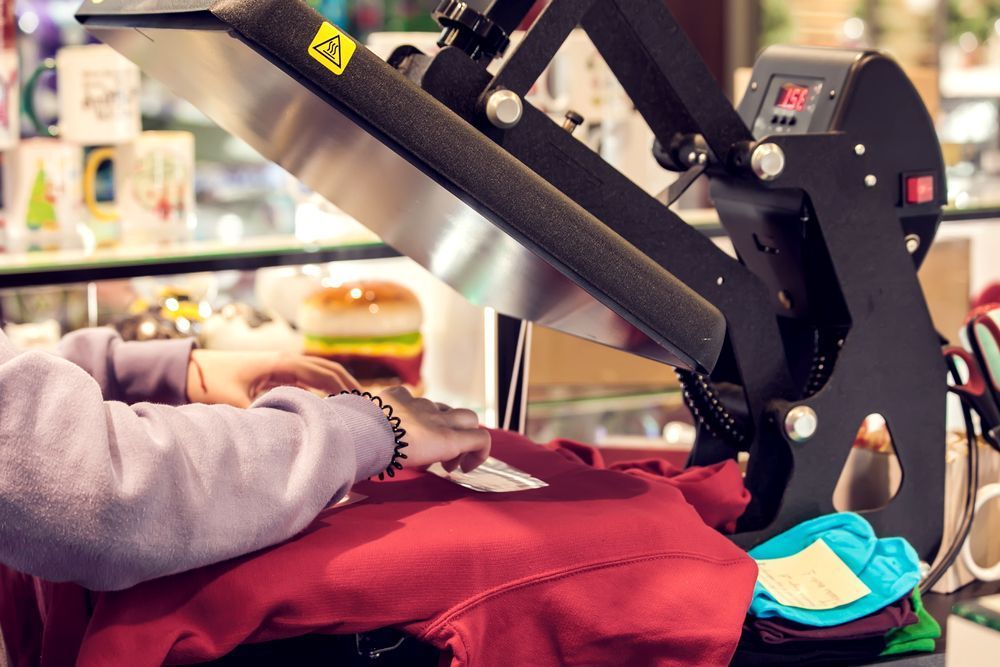 A Person Is Using a Heat Press Machine to Print a Shirt — Imsprint in East Maitland, NSW