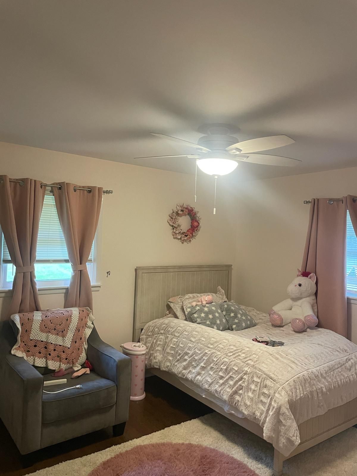 A bedroom with a bed , chair , and ceiling fan.