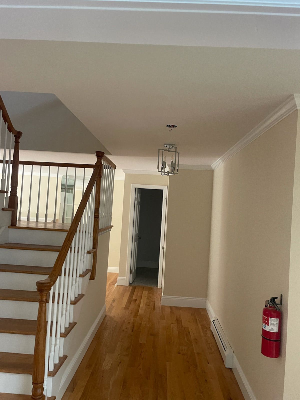 A hallway with stairs and a fire extinguisher on the wall