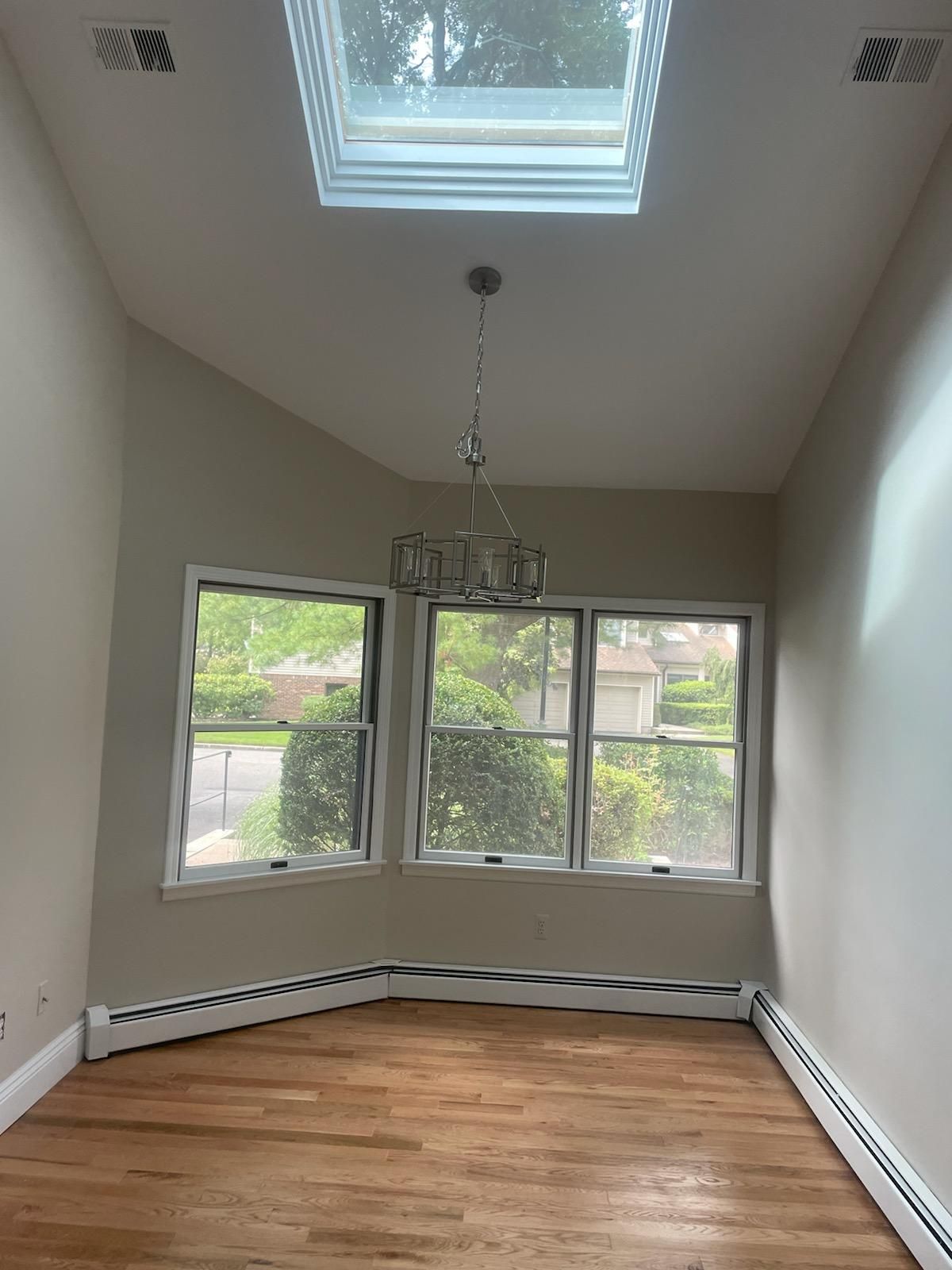 An empty room with a skylight and a chandelier hanging from the ceiling.
