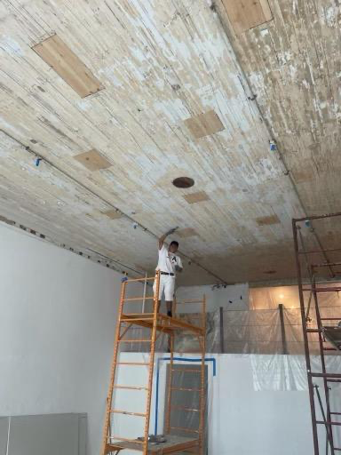 A man is standing on a scaffolding working on a wooden ceiling.