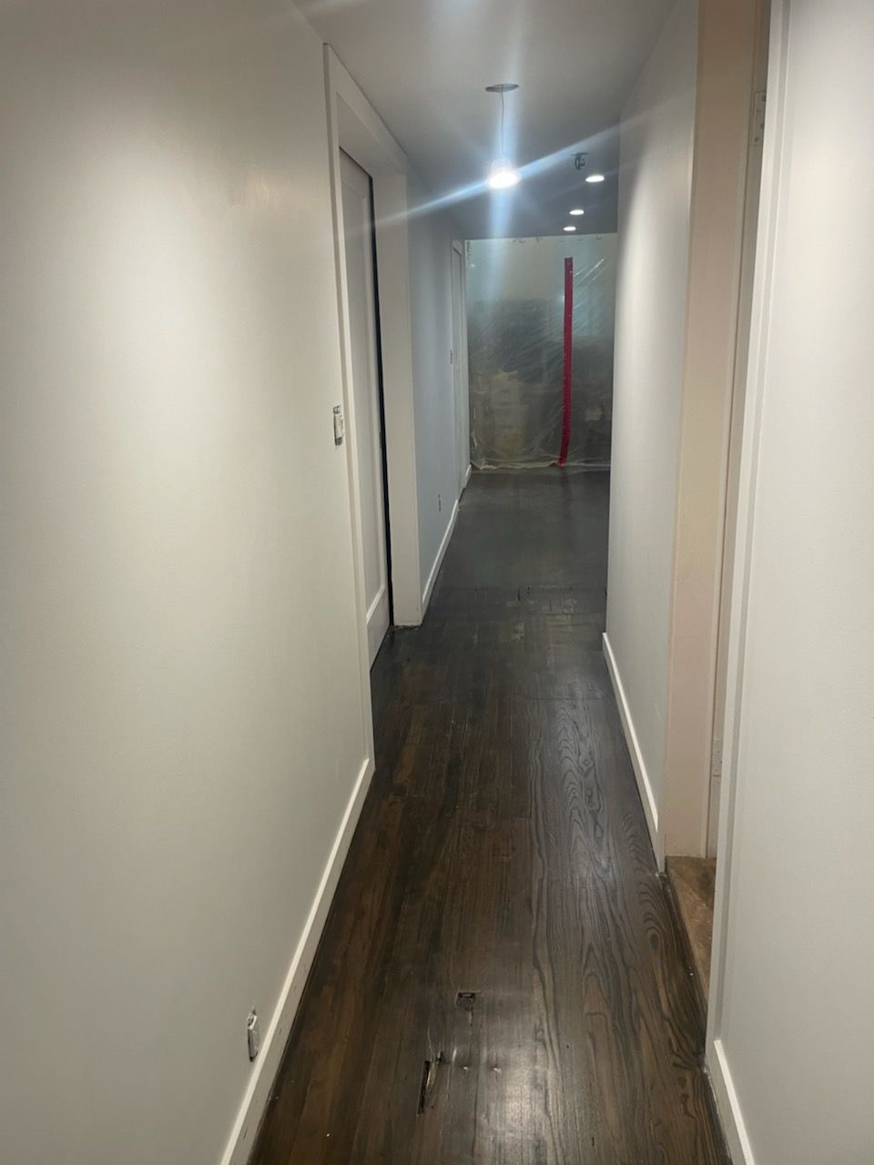 A long hallway with white walls and wooden floors