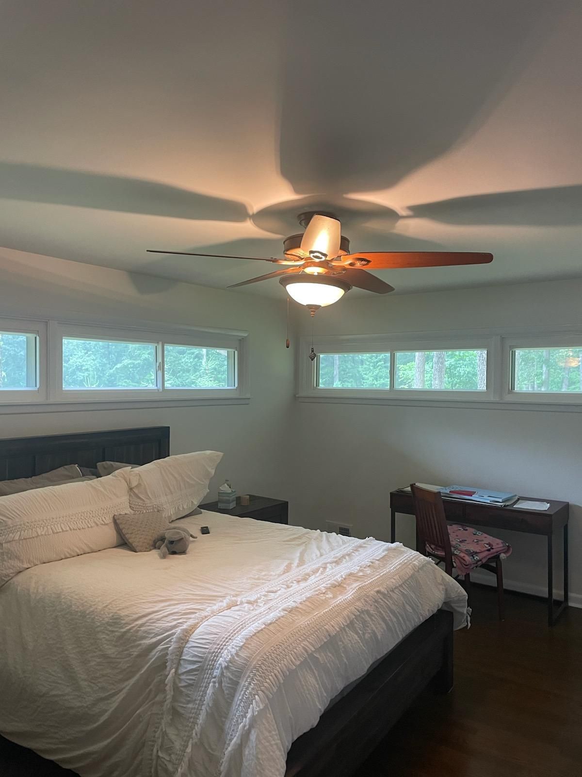 A bedroom with a bed , desk and ceiling fan.